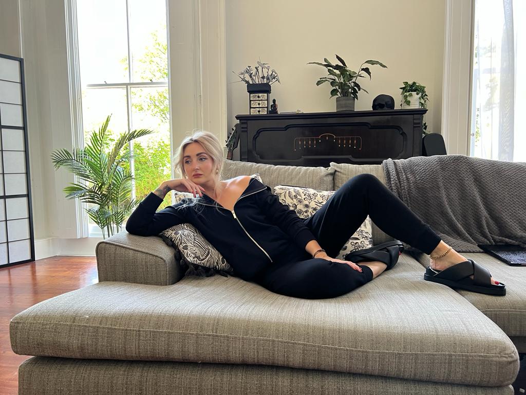 Woman wiht blonder hair laying on comfy sofa wearing Femss Elevated lounge wear in black 